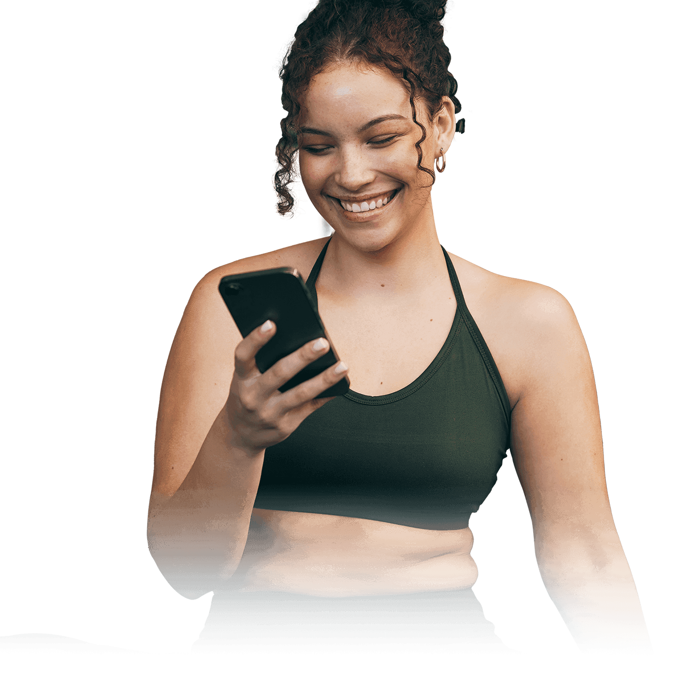 A woman smiling while looking at her phone.