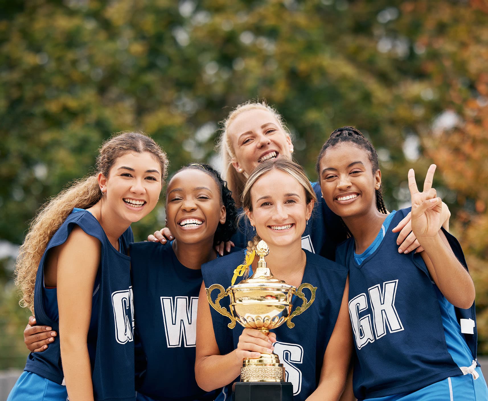 Five women posing with a trophy after winning.