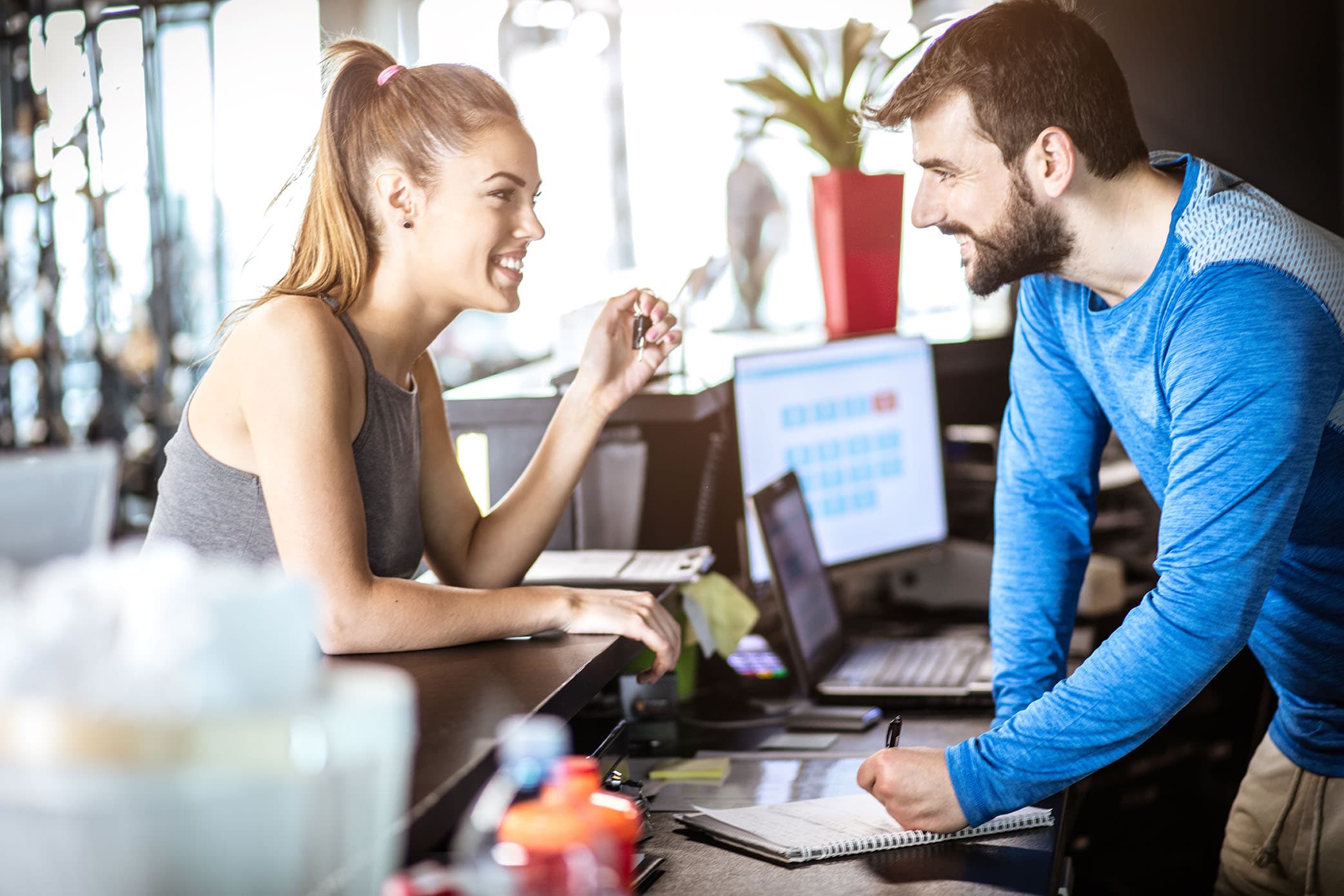 A woman having a conversation at the gym/club reception while checking in.
