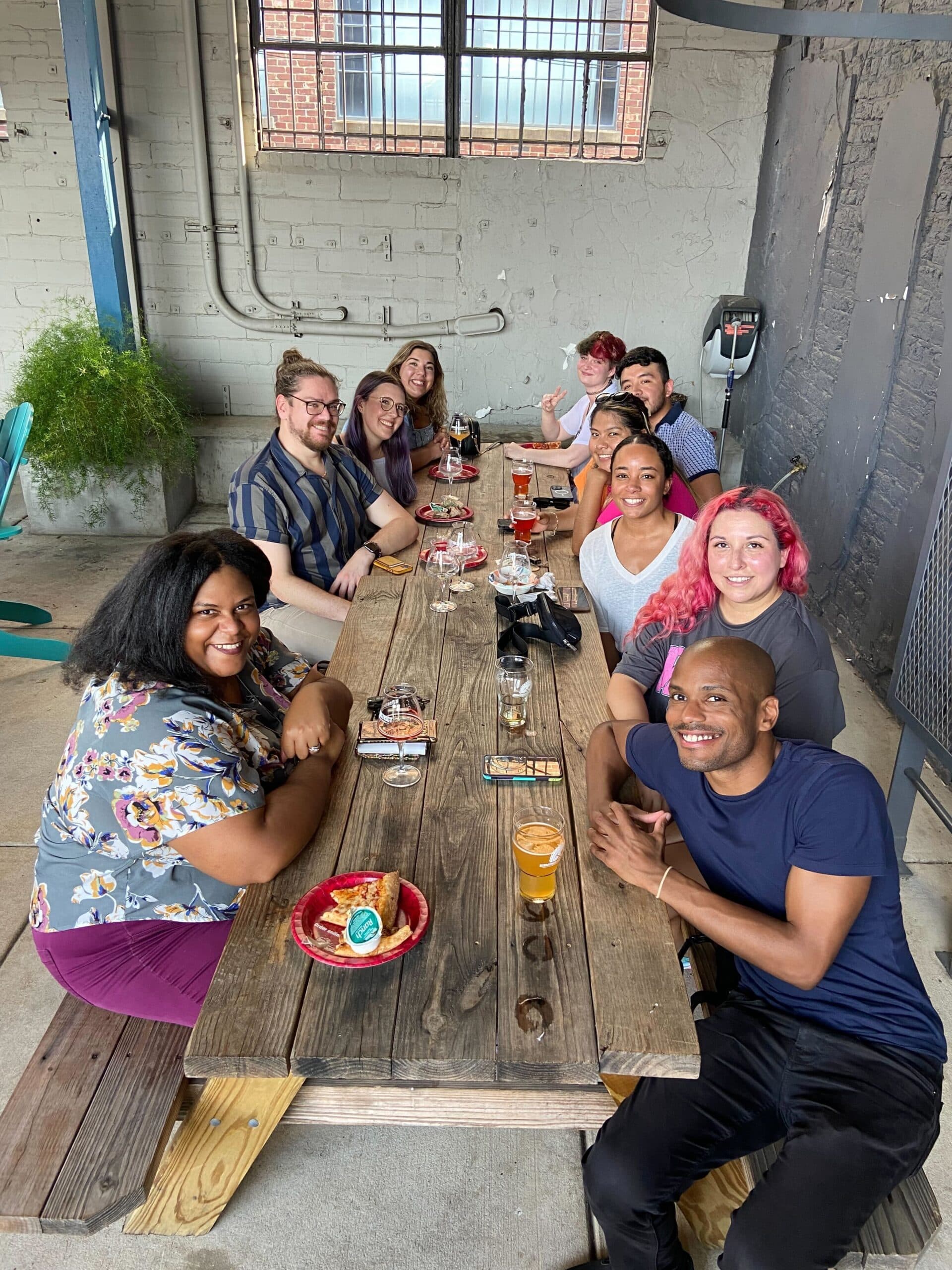 People seated together, posing for a picture while enjoying their food and drinks.