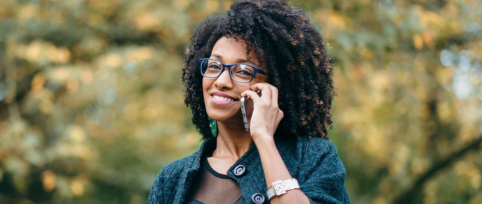 A woman with afro hair and glasses talking on a cell phone.