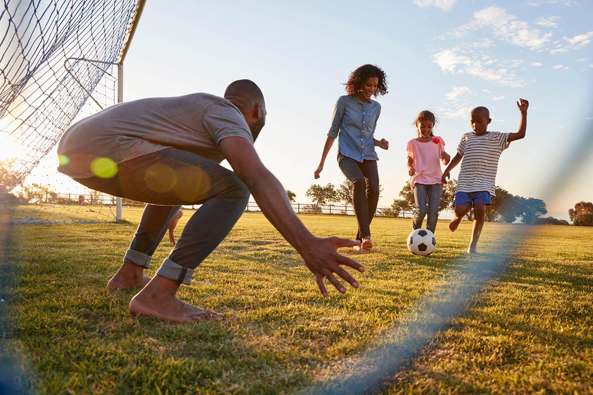 Family playing soccer at a local park